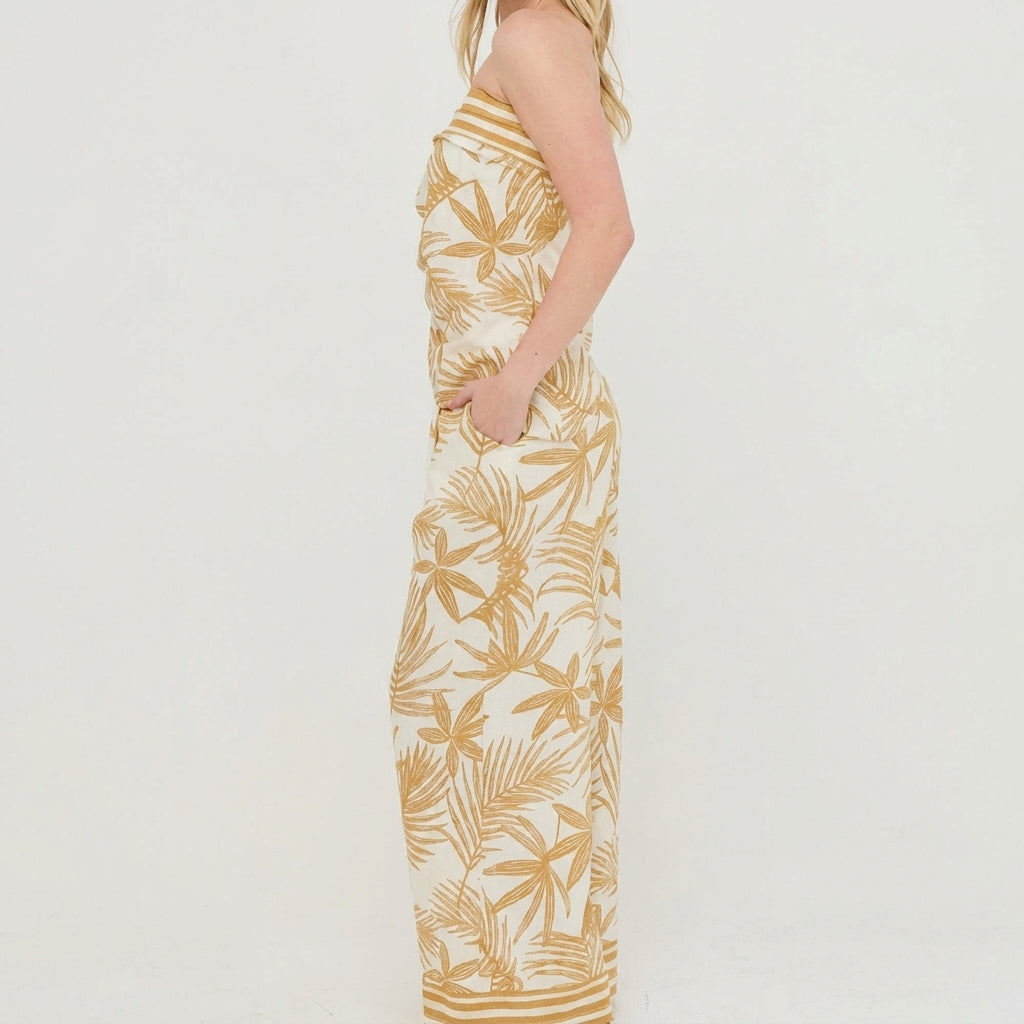 Person in a patterned strapless dress standing sideways against a white background.