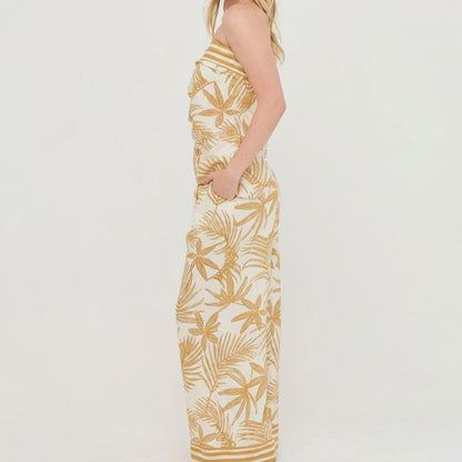 Person in a patterned strapless dress standing sideways against a white background.