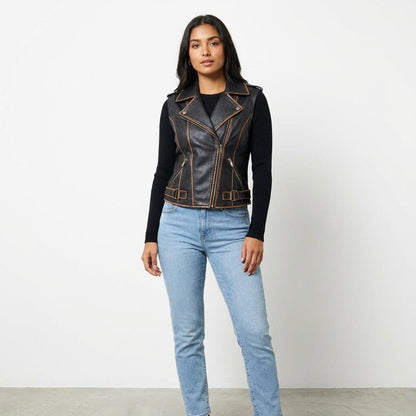 A woman models a black leather vest over a long-sleeve top and light blue jeans.