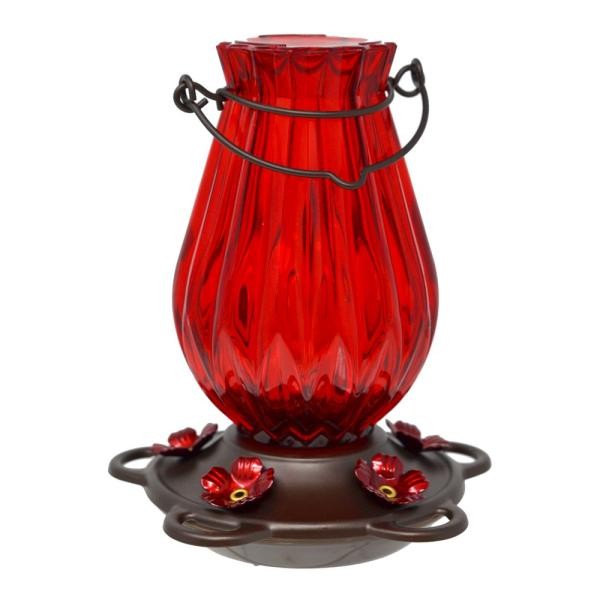 Red glass hummingbird feeder with decorative flowers and metal handle.