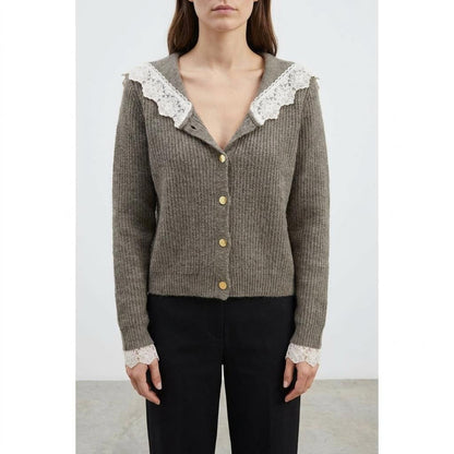 Woman in a brown cardigan with lace details and gold buttons.