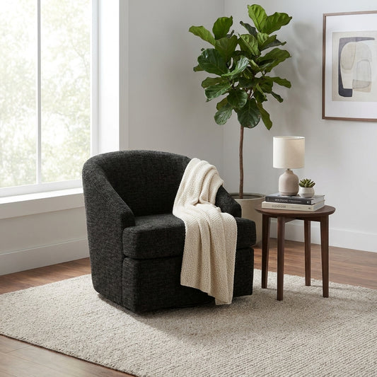 Cozy room with a black chair, side table, lamp, and plant by a window and artwork.