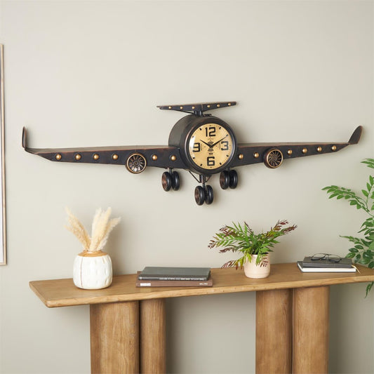 Airplane-shaped clock on wall above a wooden table with decor.