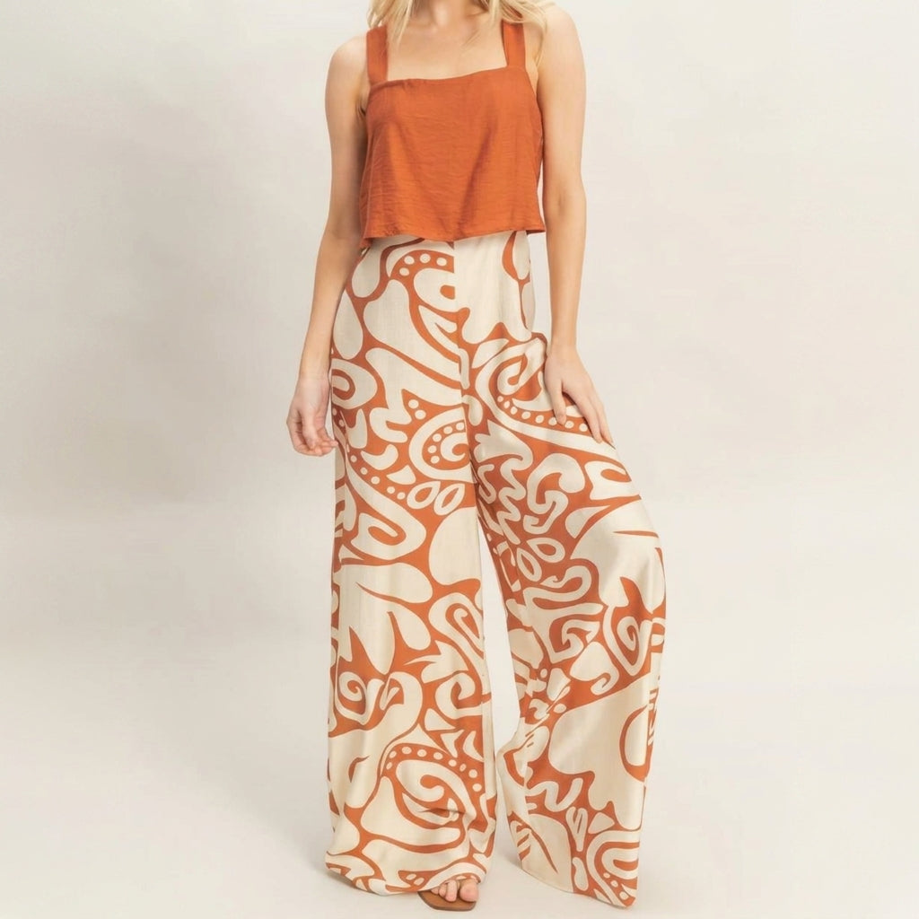 Woman in orange top and patterned wide-leg pants.