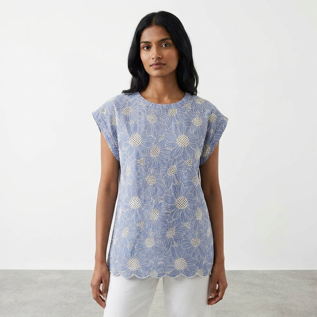 Woman in floral blue top standing against a plain background.