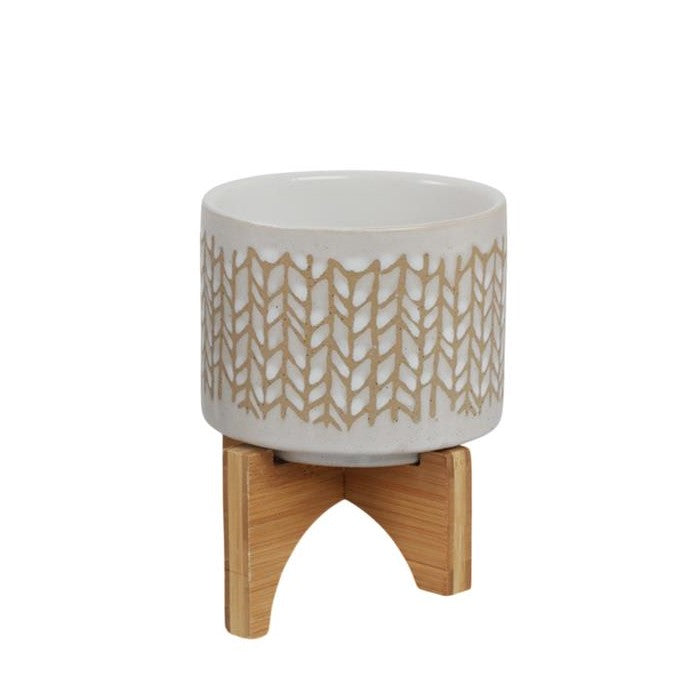 Patterned ceramic pot on a wooden stand.