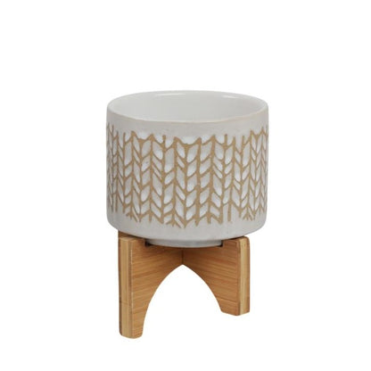 Patterned ceramic pot on a wooden stand.