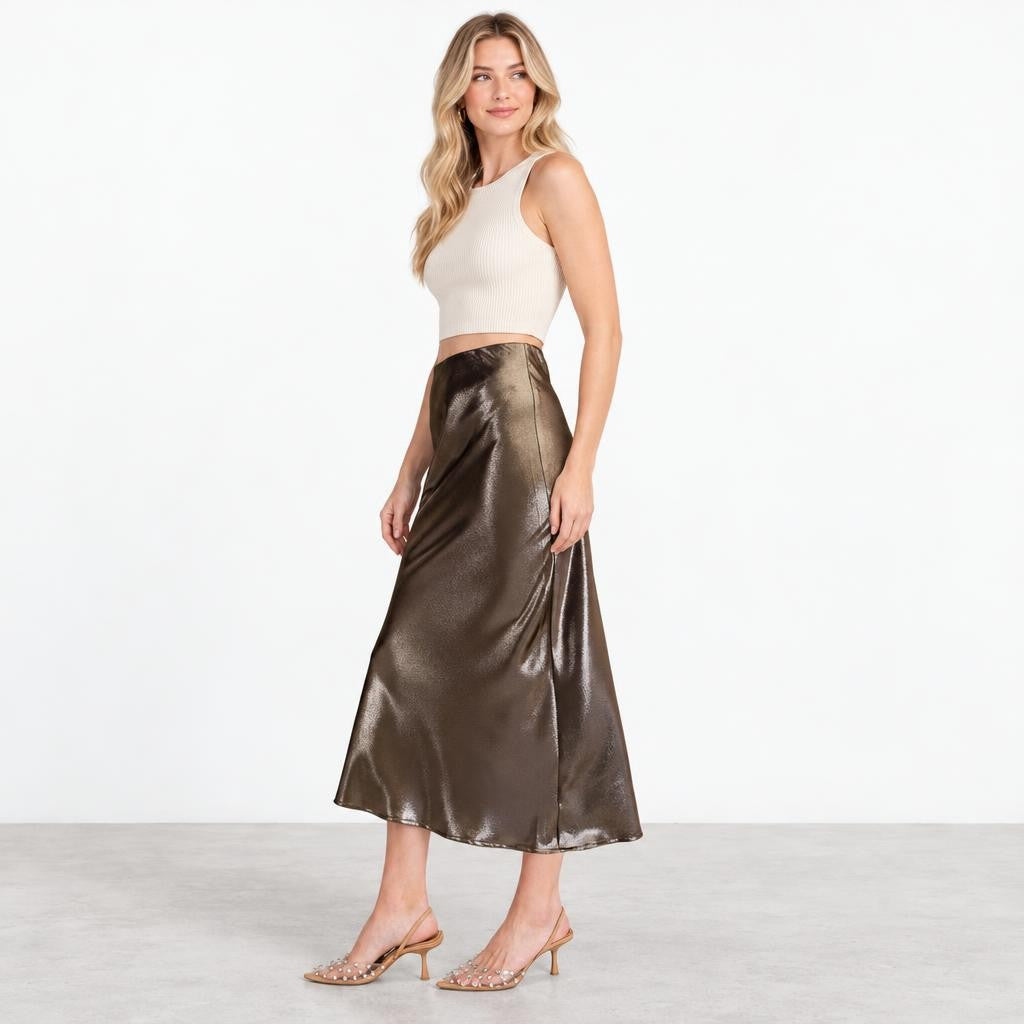 A woman models a cream crop top, bronze satin midi skirt, and strappy heels.