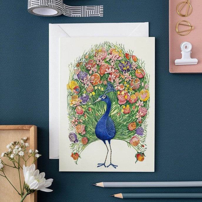 Colorful peacock illustration with floral tail on a card.