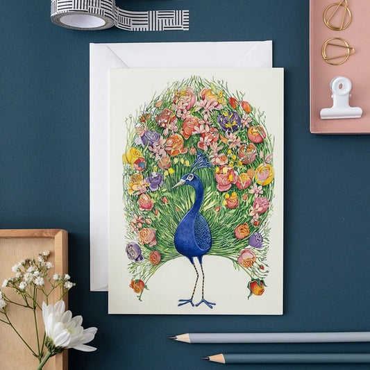 Colorful peacock illustration with floral tail on a card.
