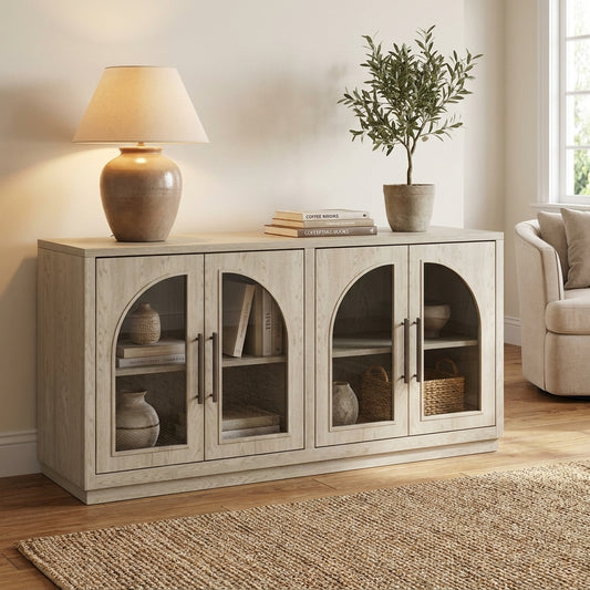 A light wood sideboard with arched glass doors, styled with a lamp, books, and a potted tree.