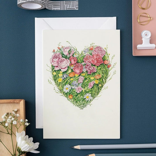 Card with a heart-shaped floral design on a blue table.