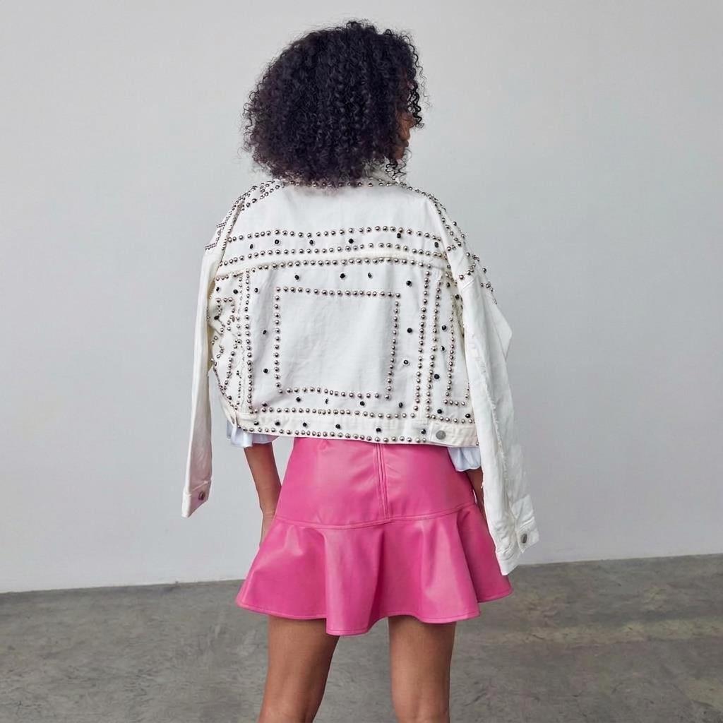 Woman in studded jacket and pink skirt turning away from the camera.