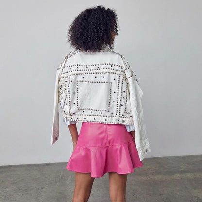 Woman in studded jacket and pink skirt turning away from the camera.