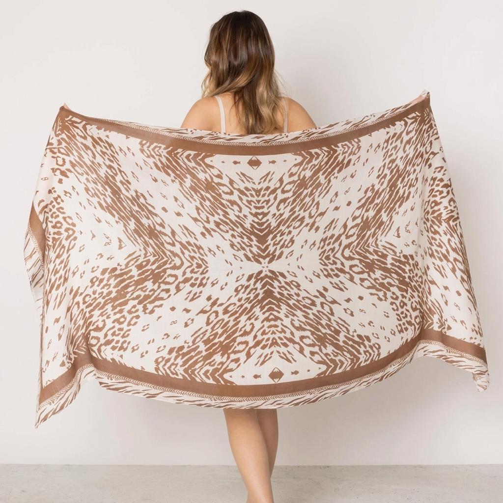 Woman holds patterned scarf with geometric design.