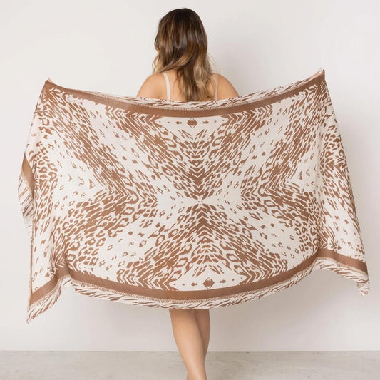 Woman holds patterned scarf with geometric design.