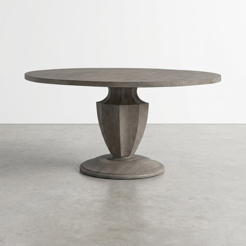 Round wooden table with sculpted pedestal base in minimalist setting.