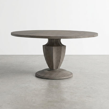 Round wooden table with sculpted pedestal base in minimalist setting.
