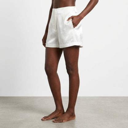 Person wearing white shorts, standing barefoot on a gray floor.