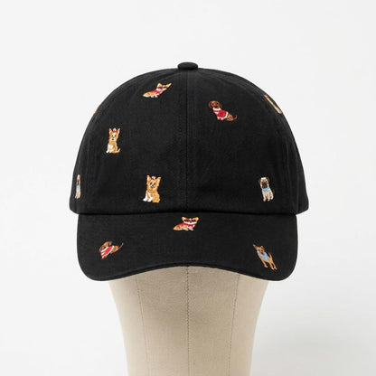 Black baseball cap embroidered with small dogs, displayed on a beige mannequin.