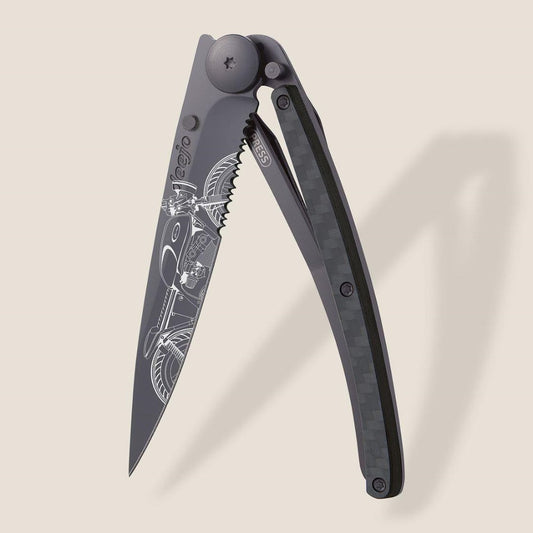 Folding knife with intricate motorcycle engraving and carbon fiber handle.