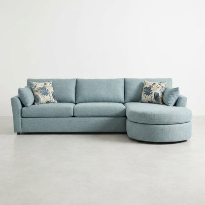 Light blue sectional sofa with floral cushions on a white background.
