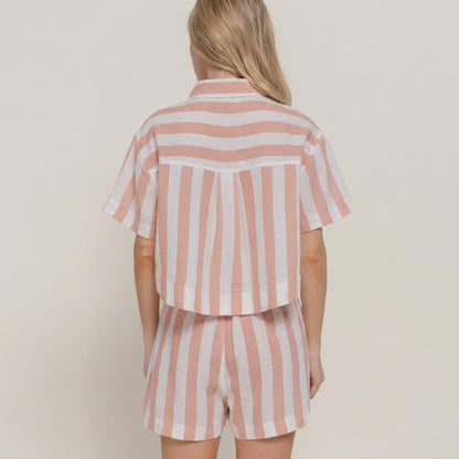 Blonde woman in pink and white striped shorts set, seen from the back.