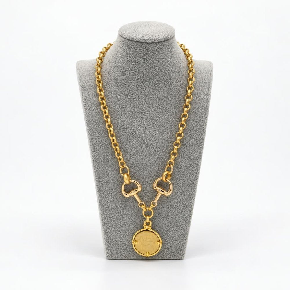 Gold chain necklace with a round pendant displayed on a gray jewelry bust.