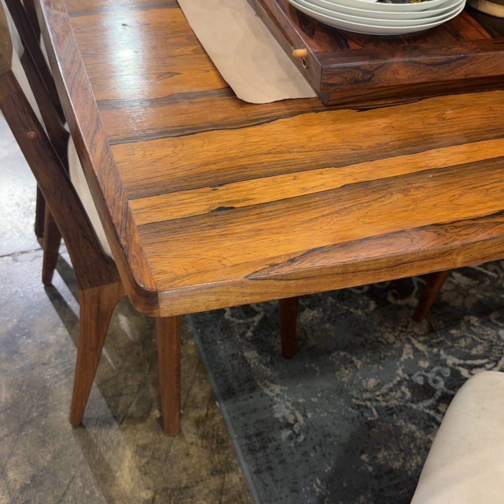 Wooden table and chairs with plates on a decorative tray.