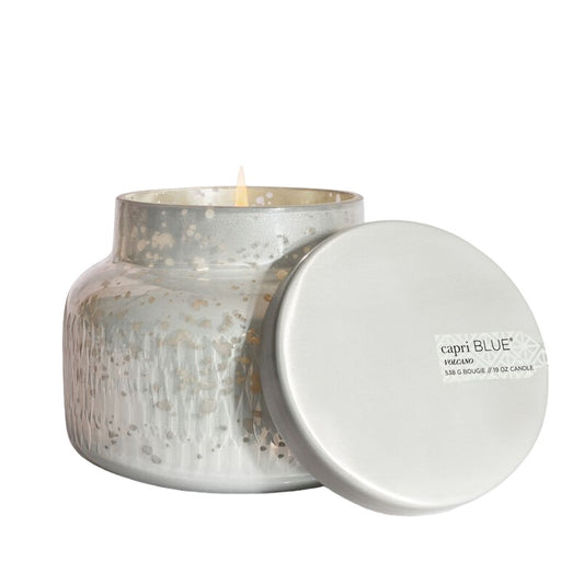 Silver glass candle with lit wick, open cover beside.