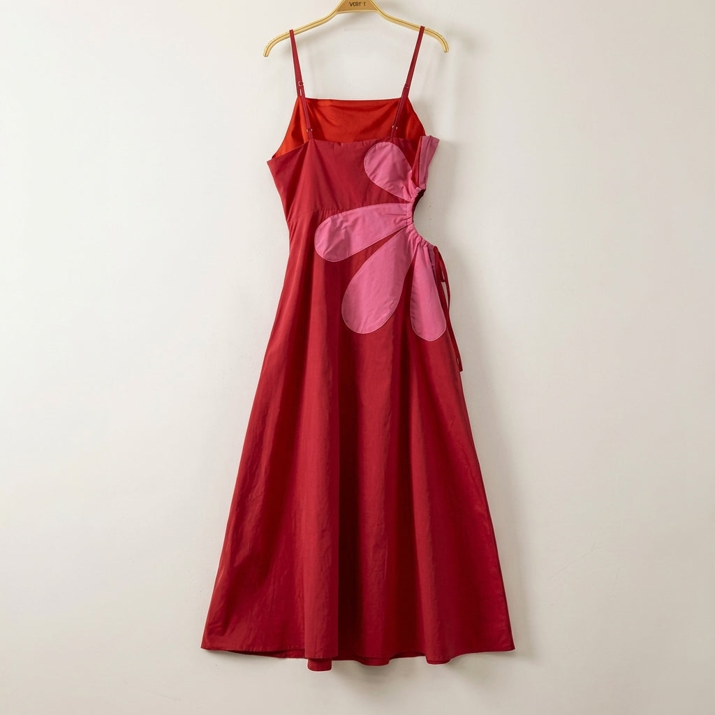 Red dress with pink flower design, hanging on a wooden hanger.