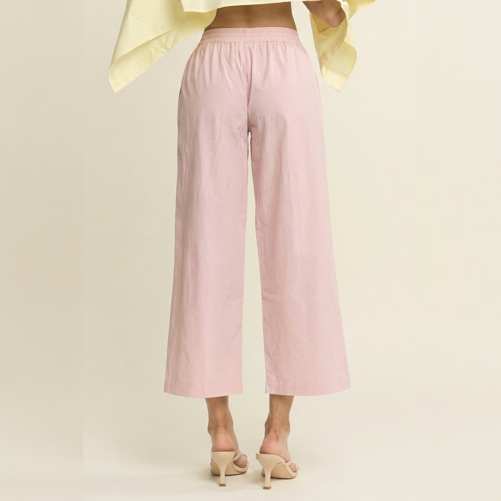 Model in pink wide-leg pants and beige heels, back view.