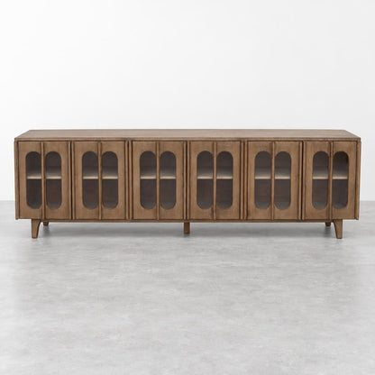 A long wooden sideboard with arched glass-panel doors stands against a plain white wall.