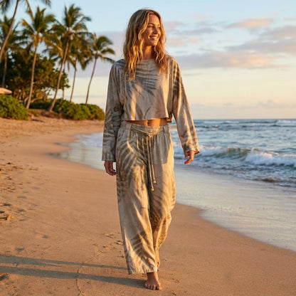 Person walking on a tropical beach at sunset, wearing a relaxed, matching outfit.