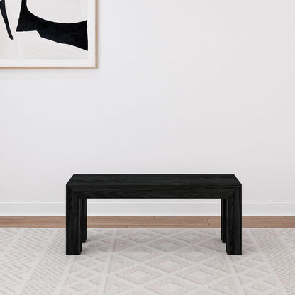 Black bench on rug, abstract artwork above.