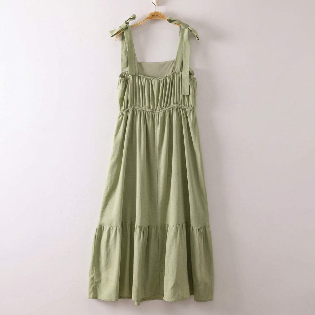 Light green dress with shoulder tie straps on a hanger.
