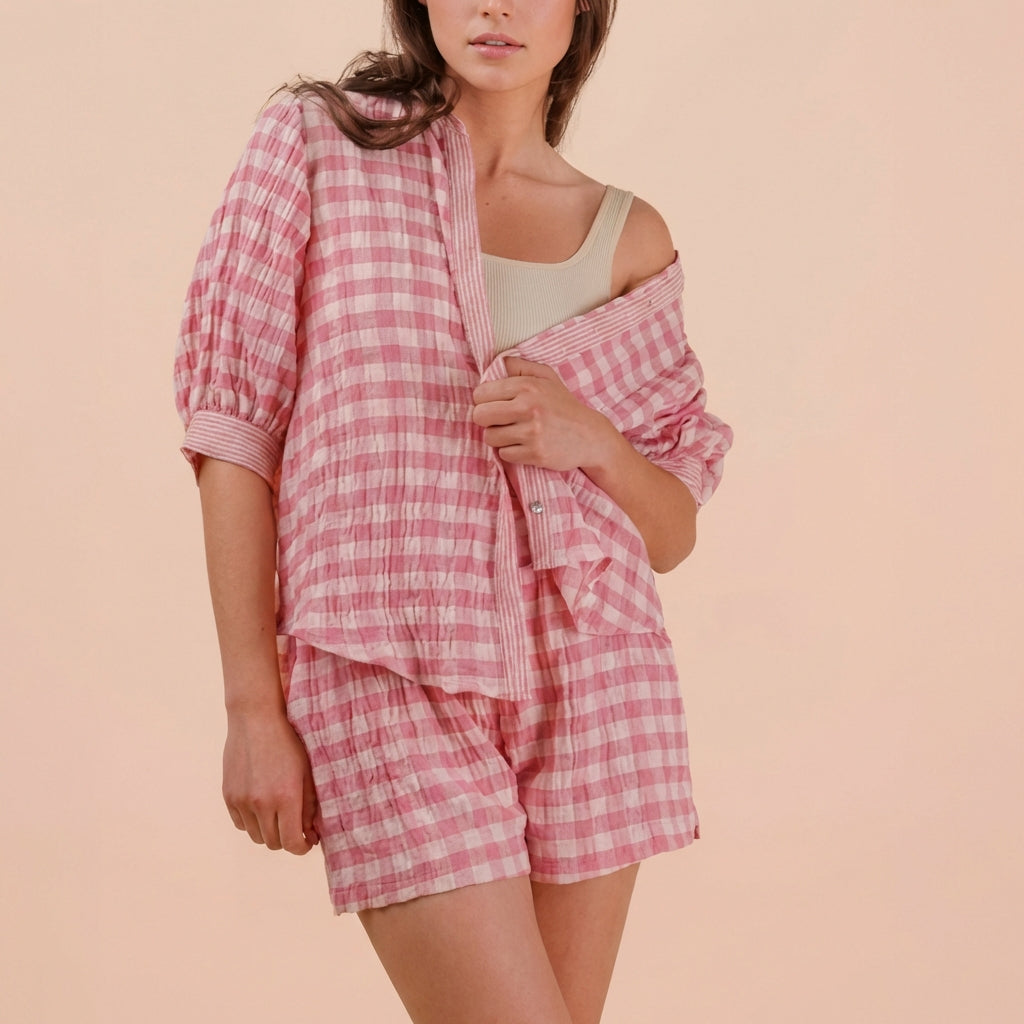 Person wearing a pink and white checkered pajama set against a beige background.