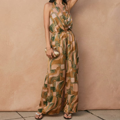Woman in a patterned jumpsuit holding a gold clutch.