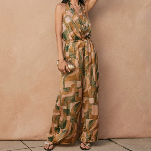 Woman in a patterned jumpsuit holding a gold clutch.
