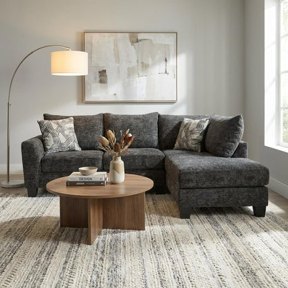 Cozy living room with a dark gray sofa, round table, and abstract art.