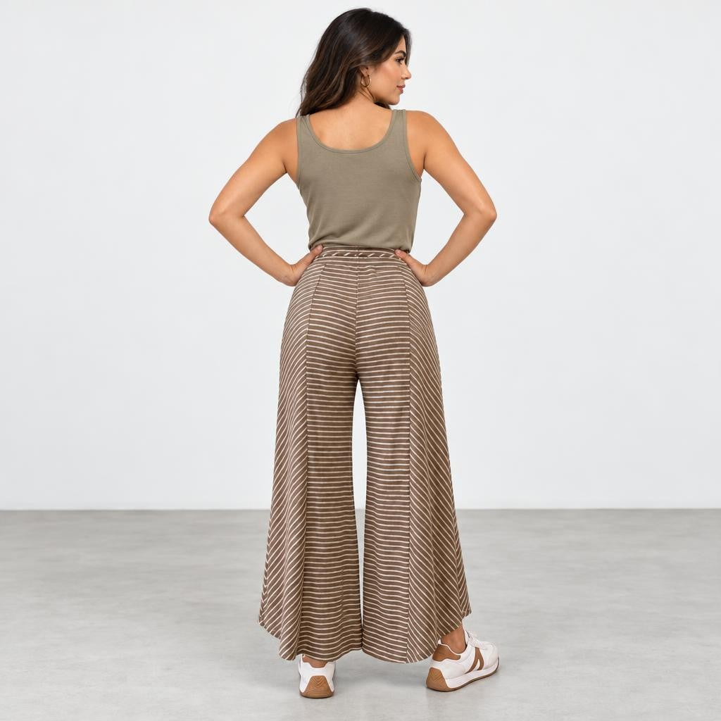 Woman in a tank top and striped wide-leg pants, standing with hands on hips.