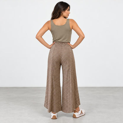 Woman in a tank top and striped wide-leg pants, standing with hands on hips.