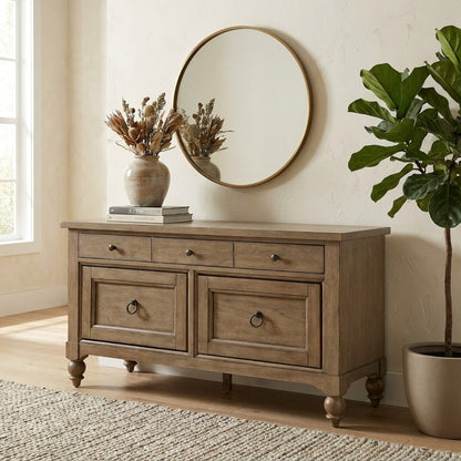 Wooden sideboard with mirror, plant, vase, and books in a bright, cozy room.