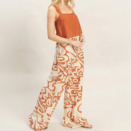 Woman in orange crop top and patterned wide-leg pants.