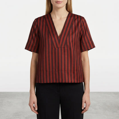 Woman in a striped V-neck top and black pants, standing against a plain background.