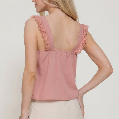 Woman in pink sleeveless top with lace details, showing back view.