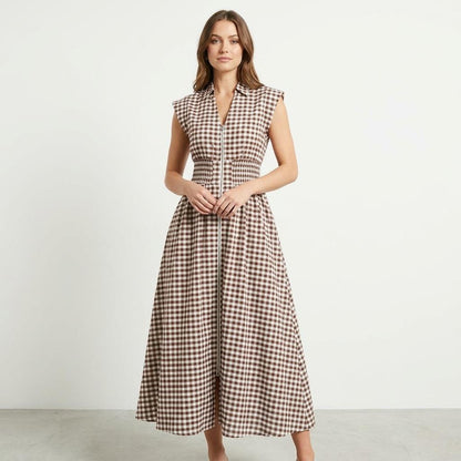 Woman in a plaid sleeveless dress on a plain background.