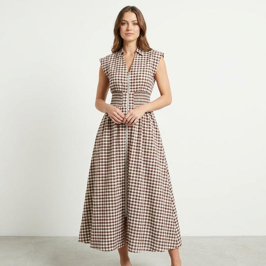 Woman in a plaid sleeveless dress on a plain background.