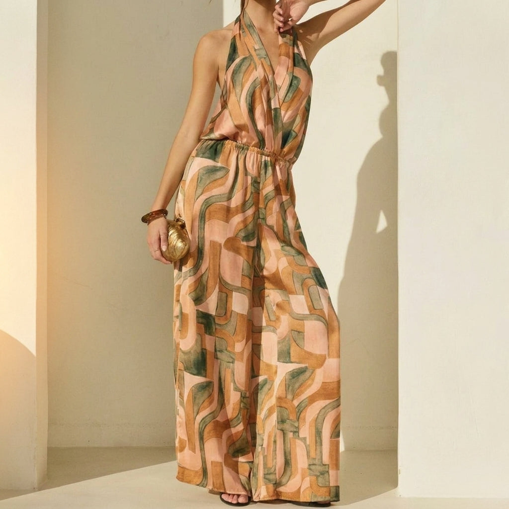 Woman in a patterned jumpsuit poses stylishly against a wall.