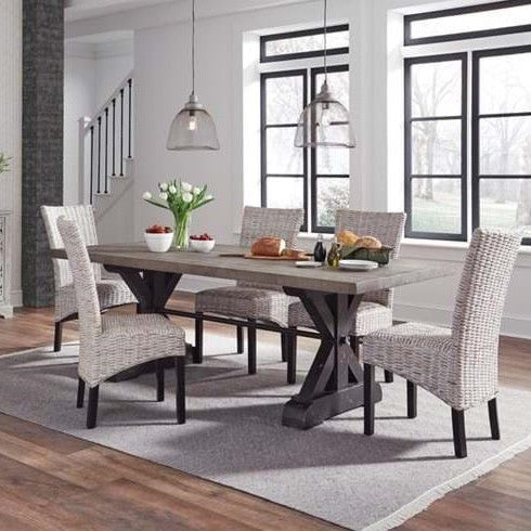 Modern dining room with a wooden table, wicker chairs, and pendant lights.